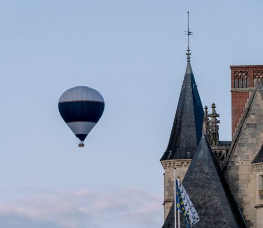 Letecký balón letí nad malebnou krajinou pri západe slnka.