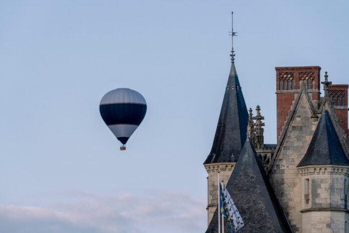 Letecký balón letí nad malebnou krajinou pri západe slnka.