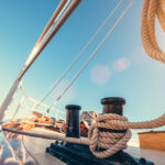 Motorová jachta a plachetnica vedľa seba na pokojnej morskej hladine, symbolizujúce ich rozdiely.