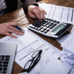 Mladý podnikateľ pracuje s notebookom pri káve a plánuje rozpočet na začiatok podnikania.