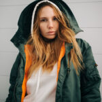 Žena skúša zimnú bundu pred zrkadlom a vyberá si strih, ktorý zvýrazní jej postavu a zároveň ju udrží v teple počas zimy.